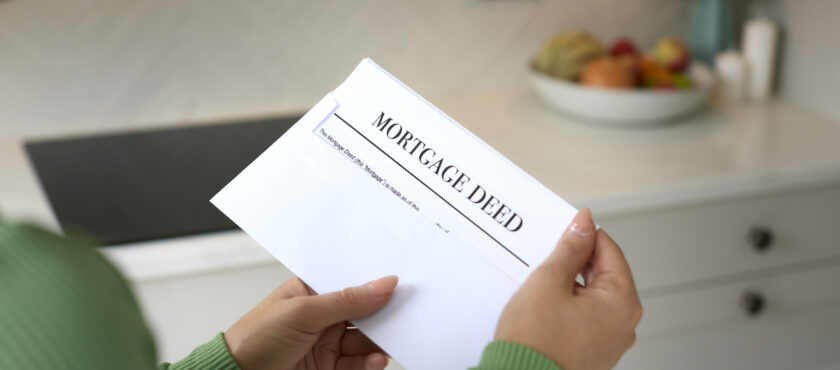 Close Up Of Woman Opening Letter Containing House Mortgage Deed