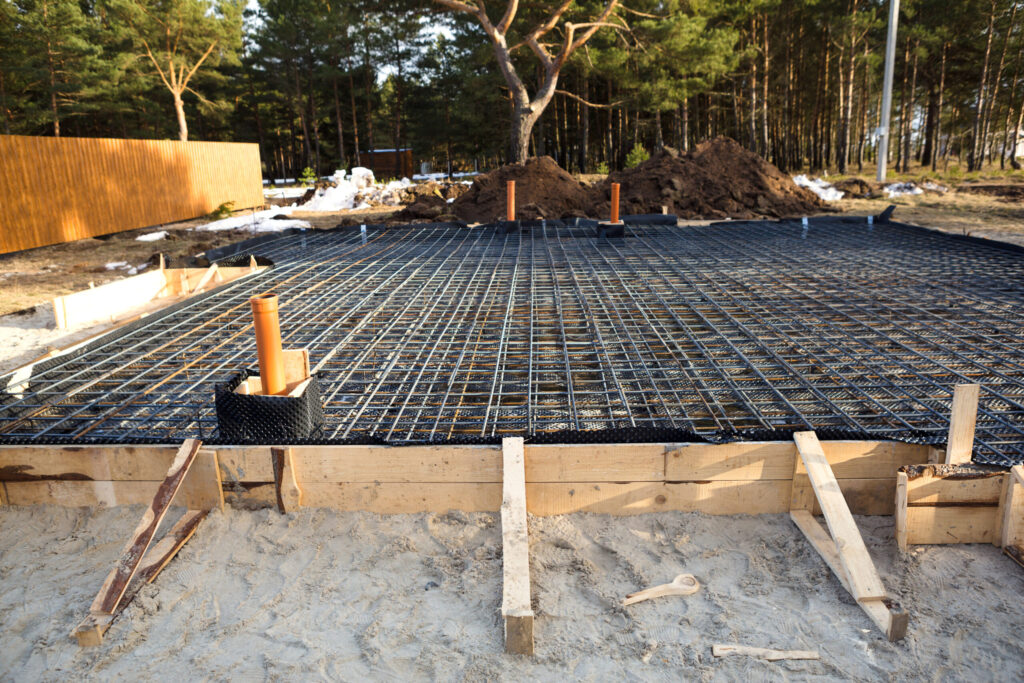 Iron fittings on a wooden formwork with laid pipes are the basis for pouring the foundation