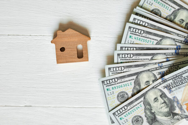 Small wooden house and hundred dollar on white background